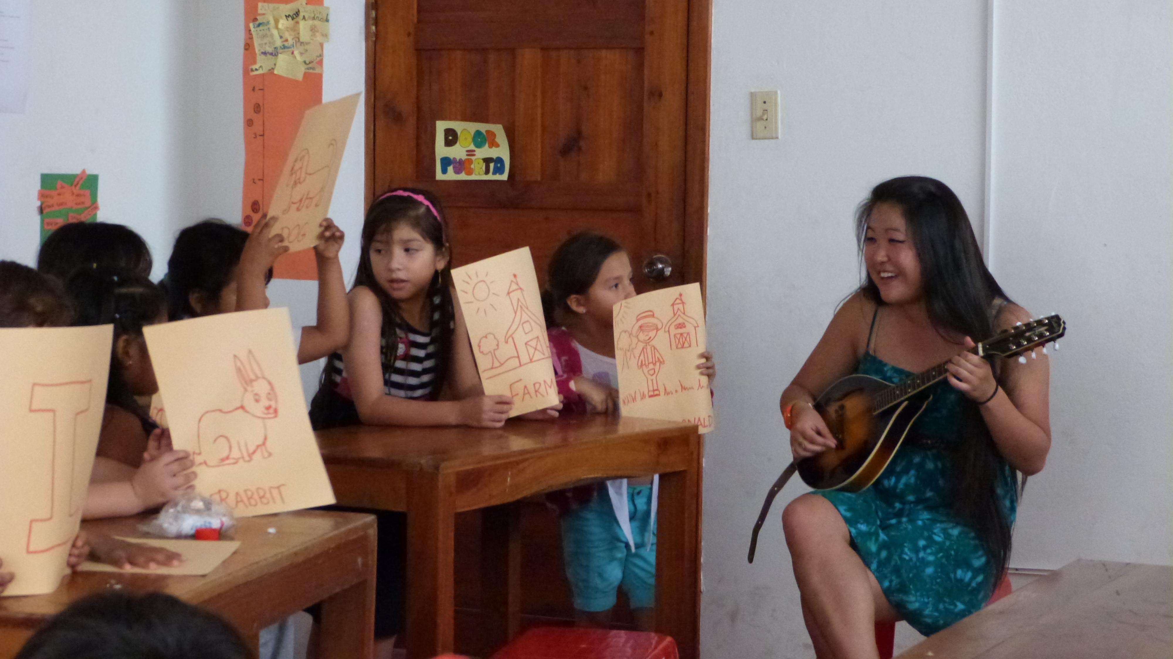 A Projects Abroad volunteer sings an English song while volunteer teaching in Ecuador Students sing along with the volunteer teaching English in Ecuador